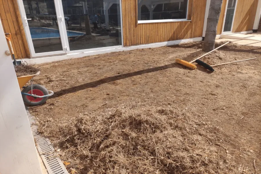 Terreno nivelado junto al edificio de madera del Camping La Escalada, en Gandía, listo para instalar césped artificial